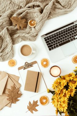 Ofis masası çalışma alanı dizüstü bilgisayarla süslenmiş sarı papatya çiçekleri, kahve fincanı, portakal dilimleri, ekose. Düz konum, üst görünüm serbest iş konsepti sosyal medya, dergi.