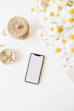 Beyaz arka planda papatya çiçeği buketi olan boş bir kopya alanı olan akıllı telefon. Düz konum, üst görünüm minimum konsept.