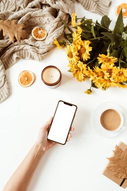 Kadınlar için ofis masası boş ekranlı akıllı telefon ve fotokopi alanı. Sarı papatya çiçekleri, süslemeler. Düz konum, üst görünüm serbest iş konsepti sosyal medya, dergi.
