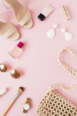 Çerçeve çerçevesi, pembe arka planda kadın aksesuarları olan yaz moda kompozisyonundan yapılmış. Çanta, parfüm, güneş gözlüğü, ayakkabı, küpe, ruj, saat. Düz konum, üst görünüm boş kopyalama alanı modeli.