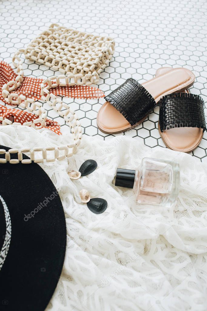 Female fashion collage with women modern accessories on white mosaic tile. Slippers, hat, purse bag, perfume, earrings, sunglasses. Lifestyle, beauty concept for blog, social media, magazine.