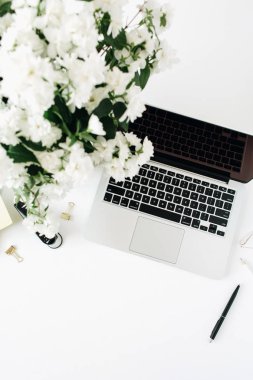 Laptop ve çiçek buketi beyaz masada. Flatlay, üst görünüm en az ofis masası arkaplanı.