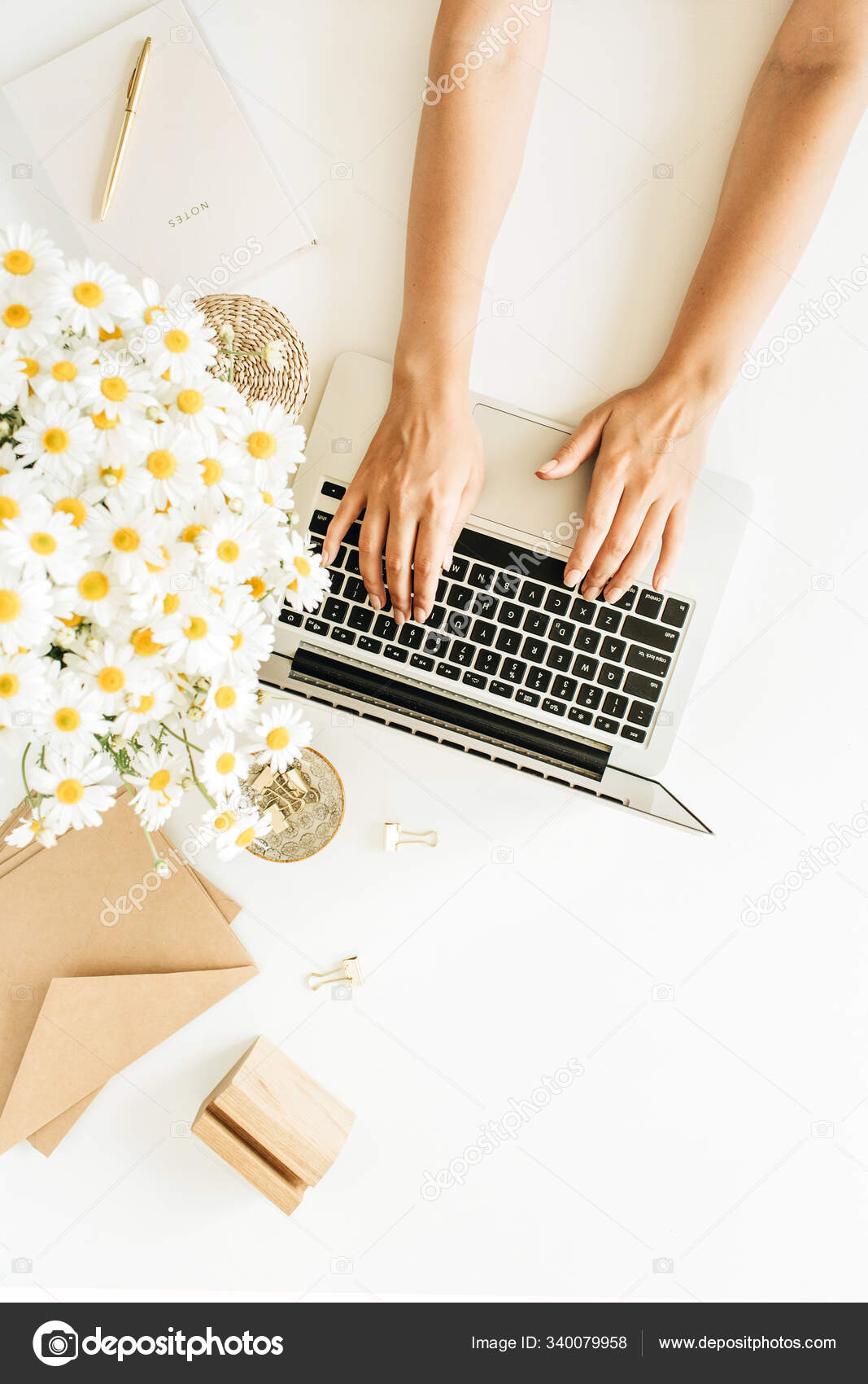 女性の手仕事の組成物 ノートパソコン付きのホームオフィスデスクワークスペース 白い背景のカモミールデイジーの花花束とノートブック フラットレイアウト トップビューコピースペースのモックアップ ストック写真 C Maximleshkovich