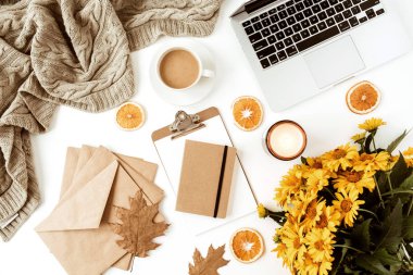 Ofis masası çalışma alanı dizüstü bilgisayarla süslenmiş sarı papatya çiçekleri, kahve fincanı, portakal dilimleri, ekose. Düz konum, üst görünüm serbest iş konsepti sosyal medya, dergi.