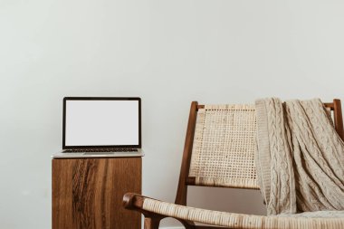 Boş maket uzay ekranlı dizüstü bilgisayar. Asgari ofis çalışma alanı. İş, iş geçmişi. Rattan ahşap koltuklu modern iç tasarım konsepti.