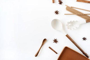 Mutfak eşyaları beyaz arka planda. Organik gıda hazırlama konsepti. Düz, üst görünüm ten rengi ahşap kap kacak. Kaşık, tarçın, anason, tabak.