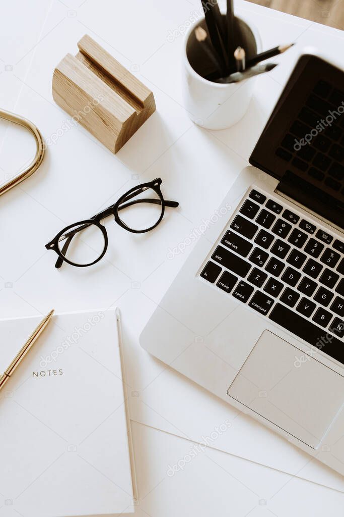 Home office desk workspace with laptop, notebook, glasses on white table. Flat lay, top view minimal women's, girl boss background.