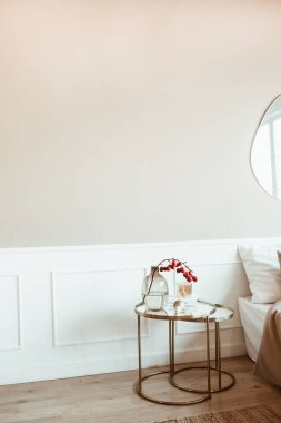 Bej duvar, komodin, cam vazoda kırmızı böğürtlen buketi ile dekore edilmiş modern klasik iç tasarım oturma odası. Rahat bir ev..