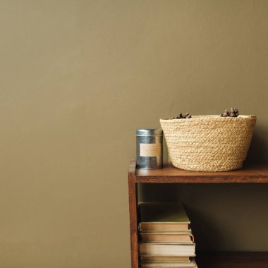 Modern iç tasarım konsepti. Hasır sepet, zeytin arka planında ahşap deste kitapları.