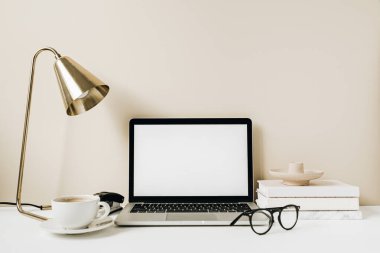 Boş ekran laptop. Kahve, lamba, gözlük, bej arka planda not defteri olan ofis masası çalışma alanı. Web sayfası şablonunu kopyala. Blogger, taşeroncu serbest kahraman başlığı.