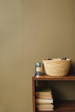 Modern iç tasarım konsepti. Hasır sepet, zeytin arka planında ahşap deste kitapları.