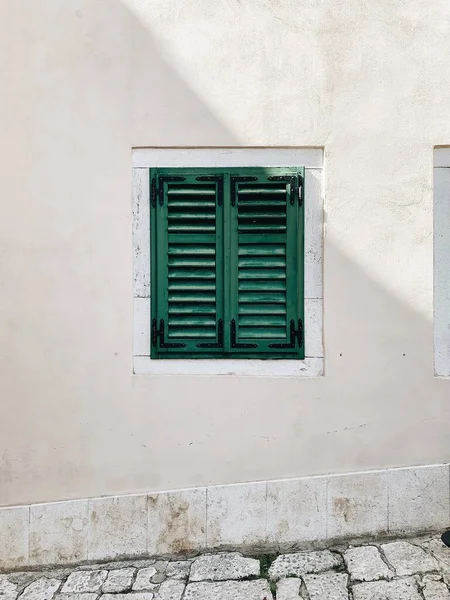 最少旅行的概念 白色建筑上孤零零的绿木窗 前面的景色欧洲传统建筑 — 图库照片