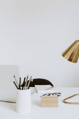 Dizüstü bilgisayarı, lambası, defteri olan çalışma alanı. Beyaz çalışma dolabı. Serbest çalışan, blogcu, patron ofisi.