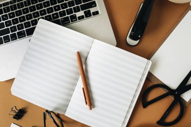 Bilgisayarlı ofis masası çalışma alanı, boş defter, gözlük, kalem, kızıl arka planda yeşil bitki dalı. Düzlük, üst görünüm kız patron iş dünyası yaşam tarzı blogu konsepti.