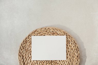 Sahte kopya alanı olan boş kâğıt levha, beton arka planda saman standı. Düz konum, üst görünüm minimal sosyal medya şablonu.