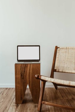 Boş maket uzay ekranlı dizüstü bilgisayar. Asgari ofis çalışma alanı. İş, iş geçmişi. Rattan ahşap koltuklu modern iç tasarım konsepti.