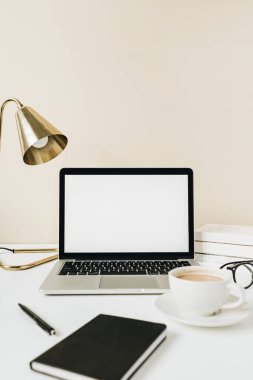 Boş ekran laptop. Kahve, lamba, gözlük, bej arka planda not defteri olan ofis masası çalışma alanı. Web sayfası şablonunu kopyala. Blogger, taşeroncu serbest kahraman başlığı.