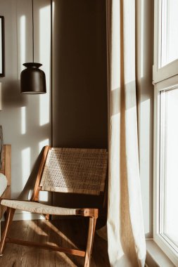 Modern şık yatak odası iç tasarım konsepti. Samimi, tarafsız İskandinav tenli, mobilyalı oturma odası. Rattan ahşap sandalye, lamba.