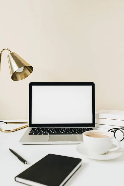 Blank screen laptop. Home office desk table workspace with coffee, lamp, glasses, notebook on beige background. Copy space mockup blog, website template. Blogger, outsourcing freelancer hero header.