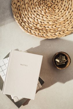 Defterler, tahta kasede klipler, bej beton arka planda saman standı. Düz yatış, üst görünüm.