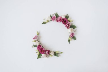 Beyaz arka planda gül çiçeklerinden yapılmış yuvarlak çelenk çerçevesi. Düz yerde, bayram kutlaması manzaralı. Metin için boş kopya alanı olan bir model