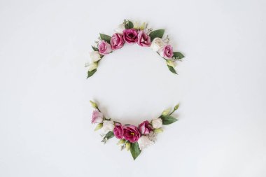 Beyaz arka planda gül çiçeklerinden yapılmış yuvarlak çelenk çerçevesi. Düz yerde, bayram kutlaması manzaralı. Metin için boş kopya alanı olan bir model