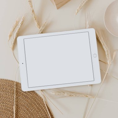 Bej arka planda, buğday sapı ve hasır peçeteli tablet. Düz konum, üst görünüm kopyalama alanı şablonu. Evde asgari iş, yaşam tarzı konsepti.