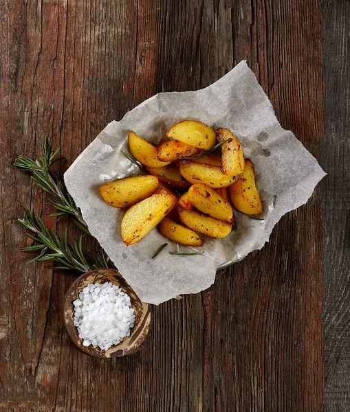 Fried Country-style Potato wedges and salt on wooden background