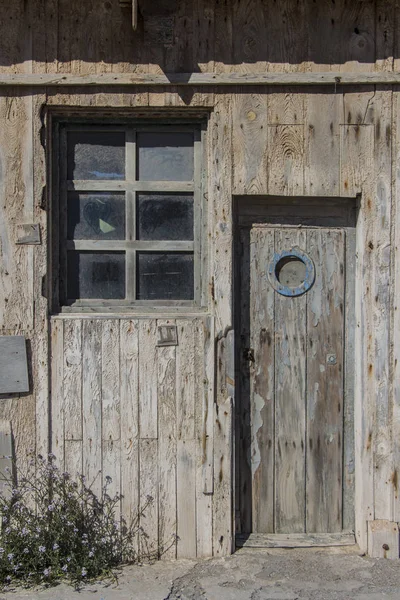 Oude houten deur met patrijspoort venster en een raam van een magazijn — Stockfoto
