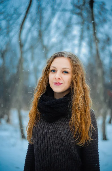 Europäisches junges Mädchen mit roten Haaren und blauen Augen auf die Natur in einem Park im Schnee bei den Winterspaziergängen — Stockfoto