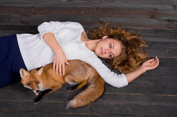 Молодая красивая девушка держит дикую лису животное, которое было травмировано человеком и спасено ею и теперь живет, как и прежде — стоковое фото