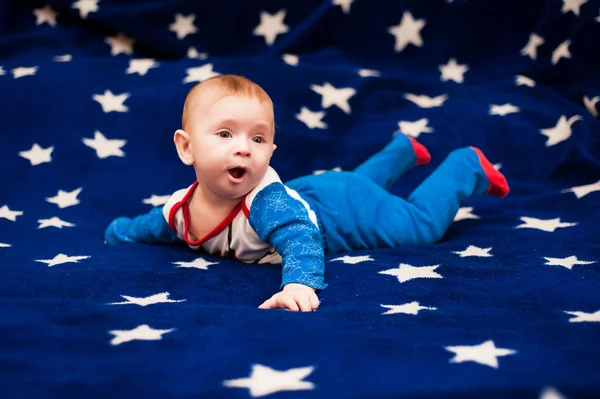 Criança 6 meses de idade e sorrindo em casa em um cobertor azul do céu estrelado — Fotografia de Stock