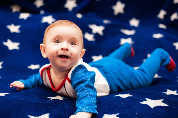 Child 6 months old and smiling at home on a blue blanket of the starry sky — Stock Photo, Image