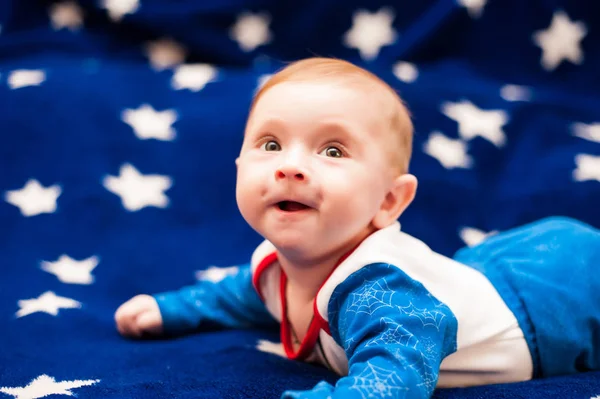 Criança 6 meses de idade e sorrindo em casa em um cobertor azul do céu estrelado — Fotografia de Stock