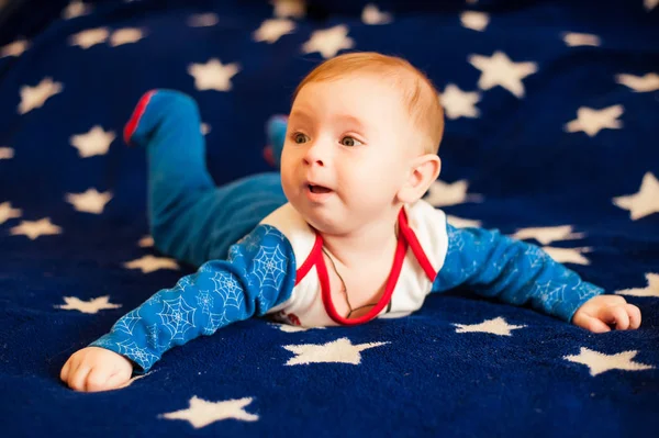 Ребенок 6 месяцев и улыбается дома на синем одеяле звездного неба — стоковое фото