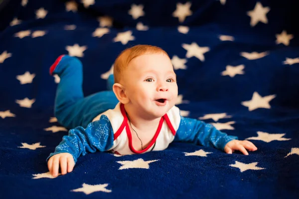 Criança 6 meses de idade e sorrindo em casa em um cobertor azul do céu estrelado — Fotografia de Stock