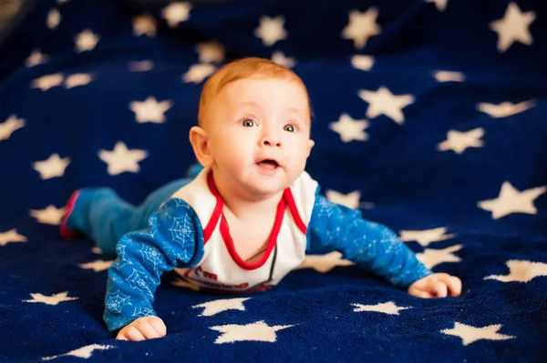 Barn 6 månader gammal och leende hemma på en blå filt av stjärnhimlen — Stockfoto