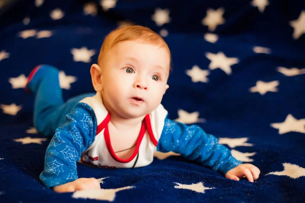 Criança 6 meses de idade e sorrindo em casa em um cobertor azul do céu estrelado — Fotografia de Stock