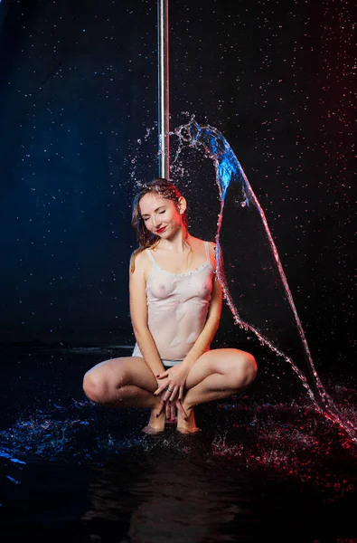 Uma jovem mulher europeia bonita em um estúdio de fotos com água está envolvida em meia-dança com abóbadas de pólo — Fotografia de Stock