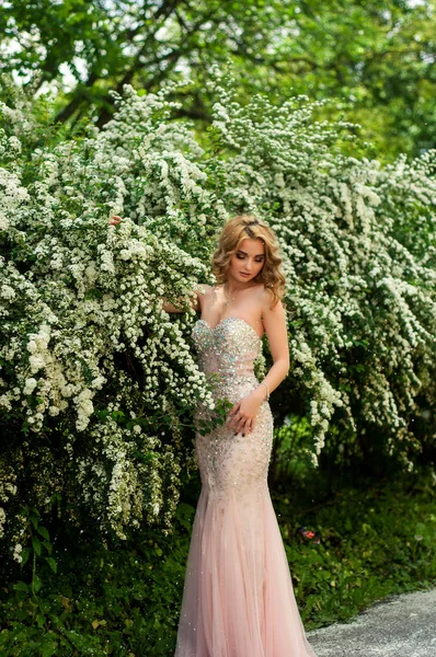 Esti koktél ruha a tavasz közepén között virágzó bokrok és fák gyönyörű, mosolygós lány — Stock Fotó