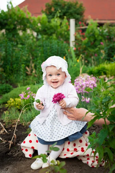 Menina 8 meses de idade Europeu ucraniano pequeno bebê em um passeio no jardim detém uma flor e morangos em suas mãos — Fotografia de Stock