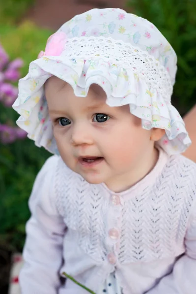Chica de 8 meses de edad bebé ucraniano europeo en un paseo por el jardín tiene una flor y fresas en sus manos —  Fotos de Stock