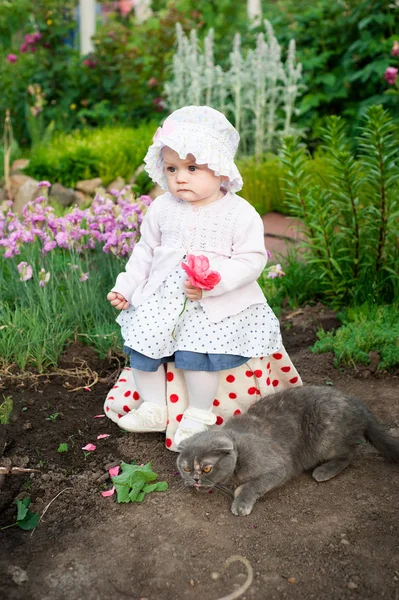 Girl 8 months old European Ukrainian little baby on a walk in the garden holds a flower and strawberries in her hands — Stock Photo, Image