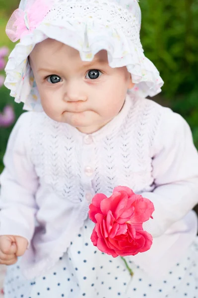 Девочка 8 месяцев Европейская украинская малышка на прогулке в саду держит в руках цветок и клубнику — стоковое фото