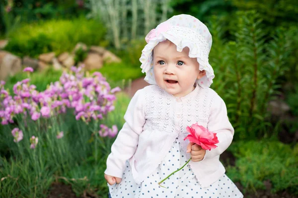 Flicka 8 månader gamla europeiska ukrainska lite baby på en promenad i trädgården lastrummen en blomma och jordgubbar i hennes händer — Stockfoto