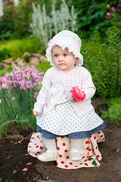 Flicka 8 månader gamla europeiska ukrainska lite baby på en promenad i trädgården lastrummen en blomma och jordgubbar i hennes händer — Stockfoto