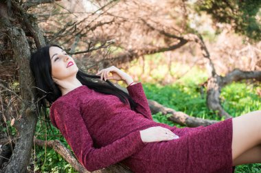 kırmızı bir elbise çiçekli ağaçlar ortasında bir bahar üzerinde bir parkta uzun saçlı güzel genç esmer