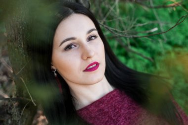 kırmızı bir elbise çiçekli ağaçlar ortasında bir bahar üzerinde bir parkta uzun saçlı güzel genç esmer