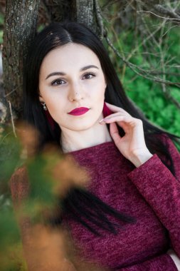 kırmızı bir elbise çiçekli ağaçlar ortasında bir bahar üzerinde bir parkta uzun saçlı güzel genç esmer