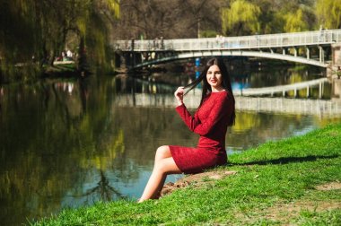 Manolya çiçek çiçekli ağaçlar elinde kırmızı bir elbise arasında baharda bir bahar üzerinde bir parkta uzun saçlı güzel genç esmer tutar